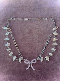 a necklace with a bow and pearls on it